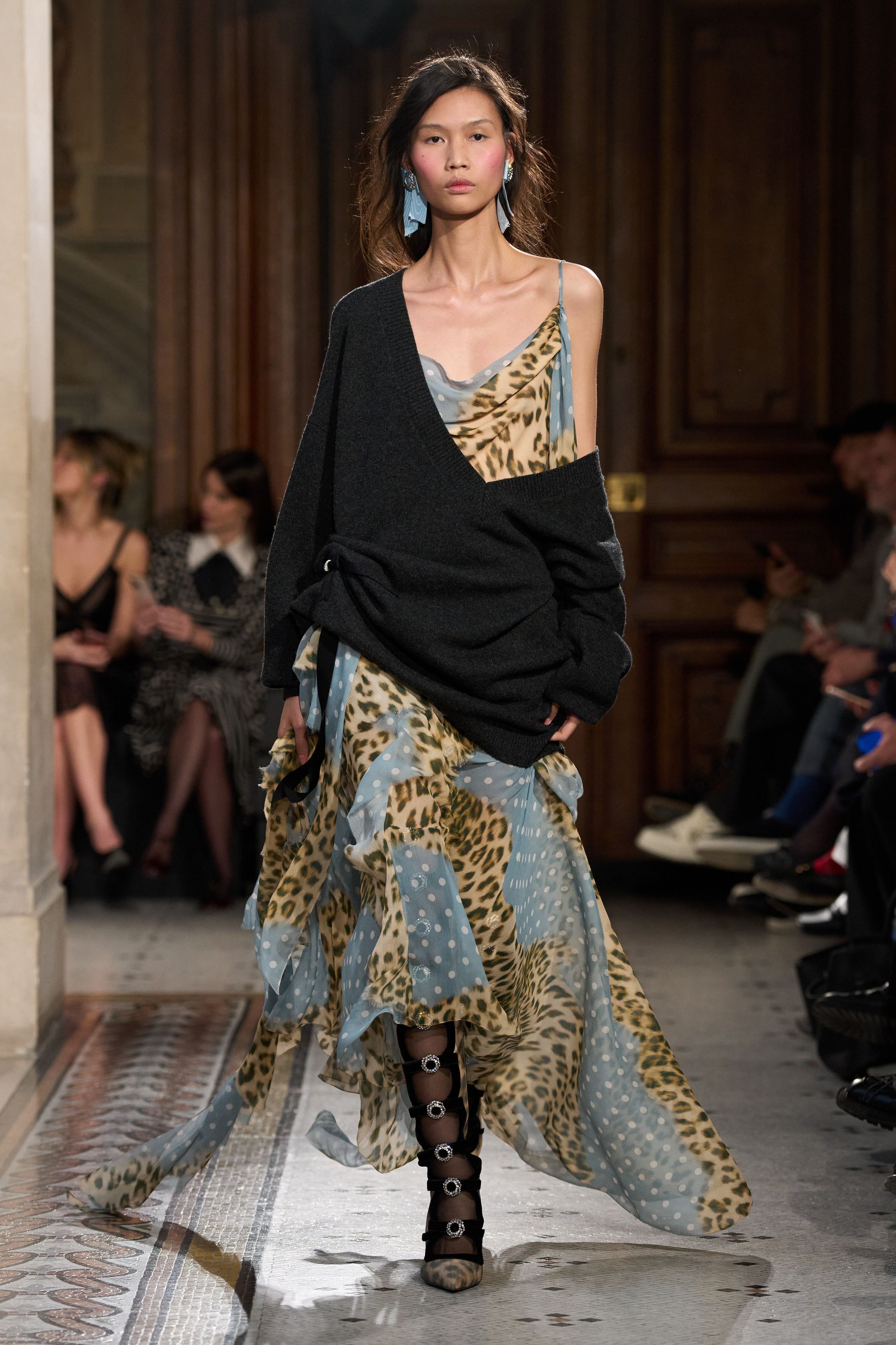 这一季 Nina Ricci 在经典巴黎优雅中加入更具戏剧张力的女性表达：黑色立体蝴蝶结装饰、豹纹雪纺长裙与结构西装形成鲜明对比，柔软与力量交织。轻薄面料与不对称层叠裙摆让整体轮廓更具流动感，既保留品牌浪漫基因，又带出一种现代女性的自信与锋芒-顽石频道趋势研究
